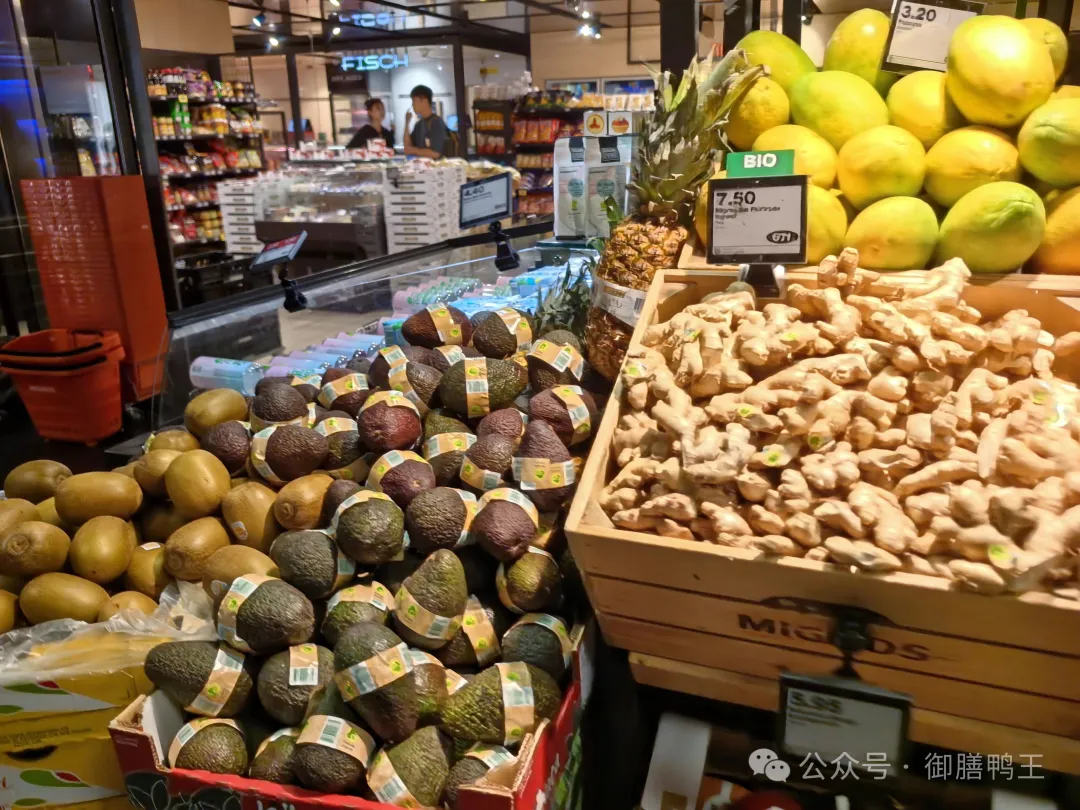 Swiss supermarket produce section with ginger, avocados, and citrus.